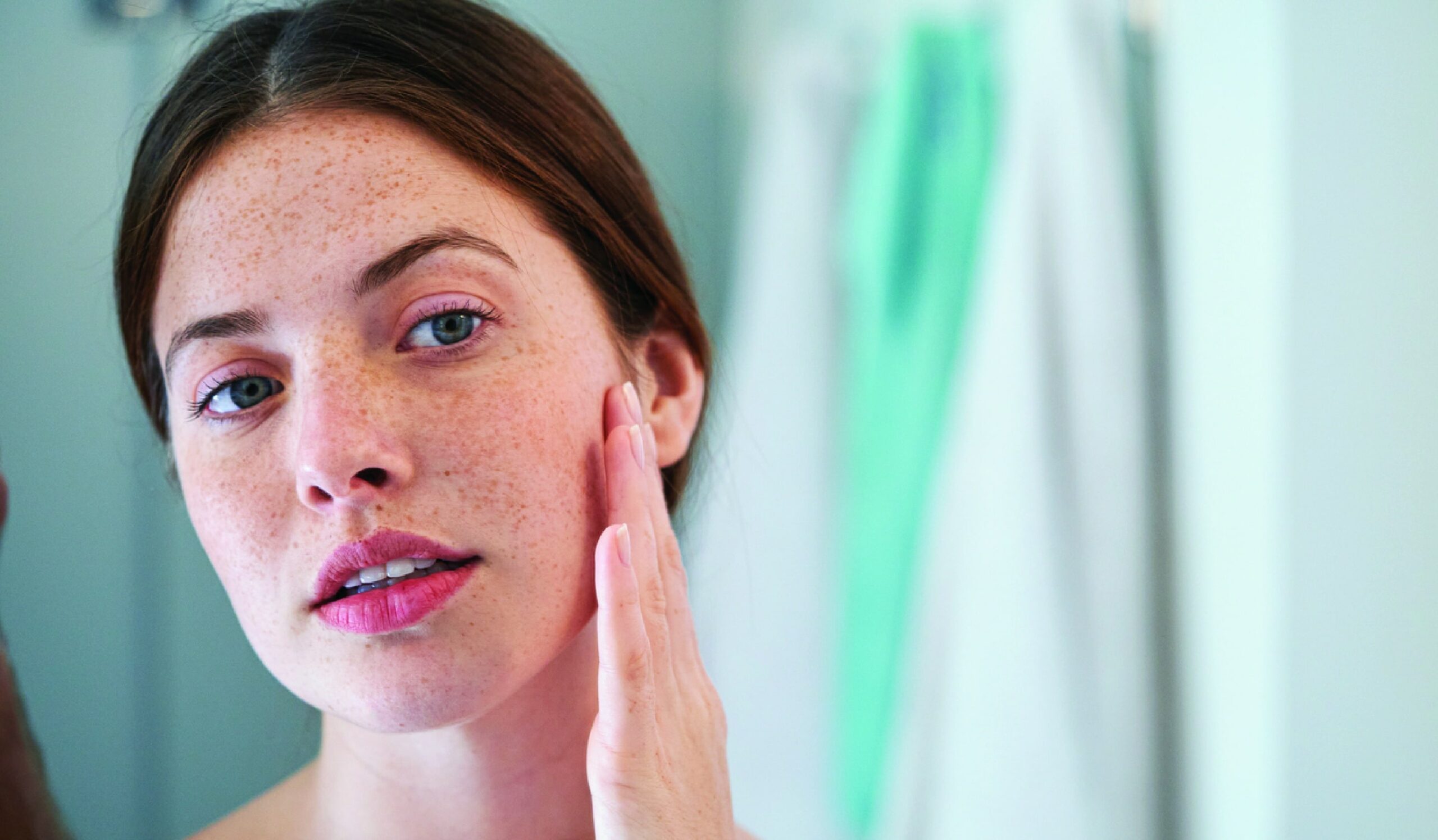 A woman looking in the mirror, admiring her enhanced nose after a successful rhinoplasty procedure.
