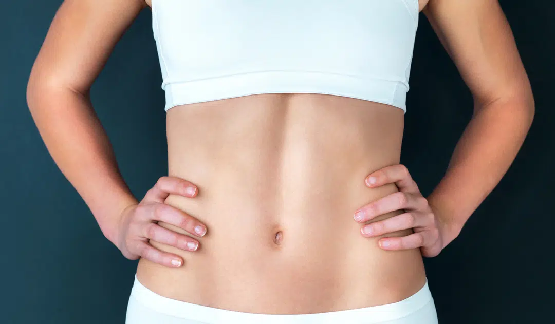 Fit girl stomach. White athletic outfit hands on hips